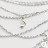 Macro detail of the infinity-symbol charm on the layered necklace