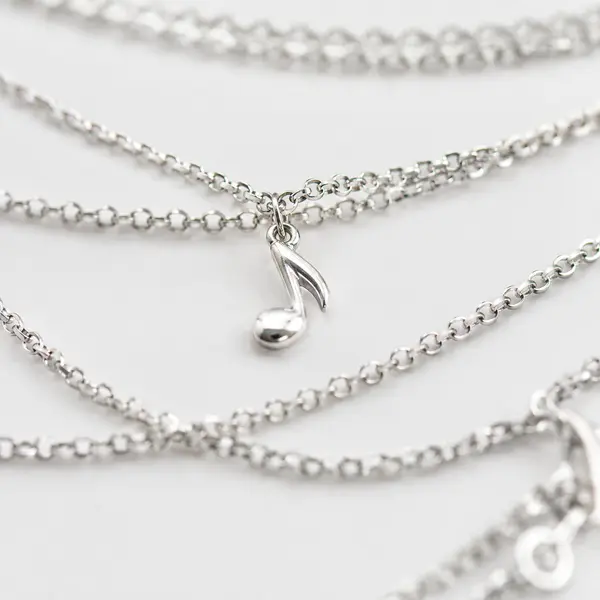 Macro detail of the infinity-symbol charm on the layered necklace