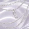 Macro detail of the silver music-note charm and fine chain