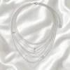 AOI multi-layer silver necklace arranged on pearl satin