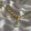 ISLA gold-tone serpent necklace with olive-green beads on pearl satin
